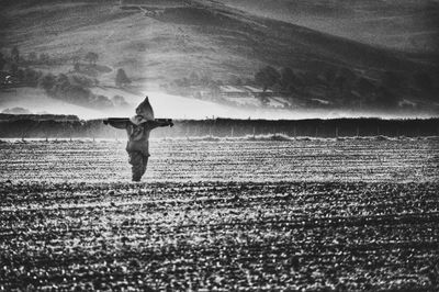 Rear view of man standing on field against sky