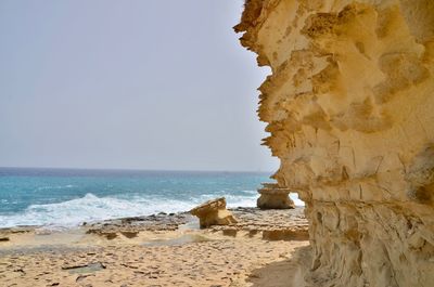 Rock formations on beach against clear sky