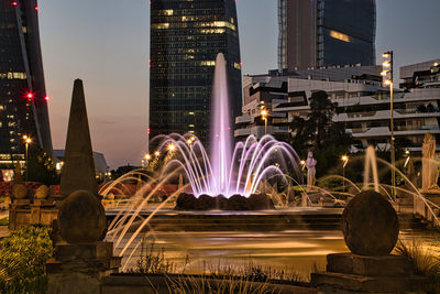 View of fountain with buildings in city at night