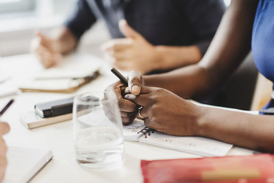 Cropped image of man and woman with smart phone sitting at table