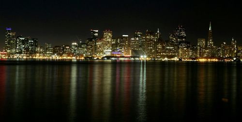 Scenic view of river by illuminated cityscape at night