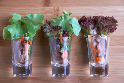 Close-up of vegetables in drinking glass on wooden table