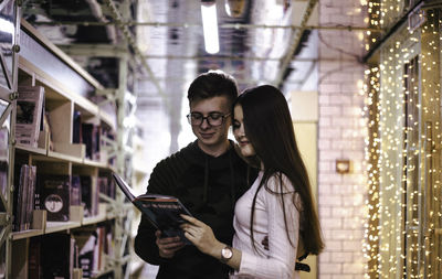 Young couple standing against illuminated wall