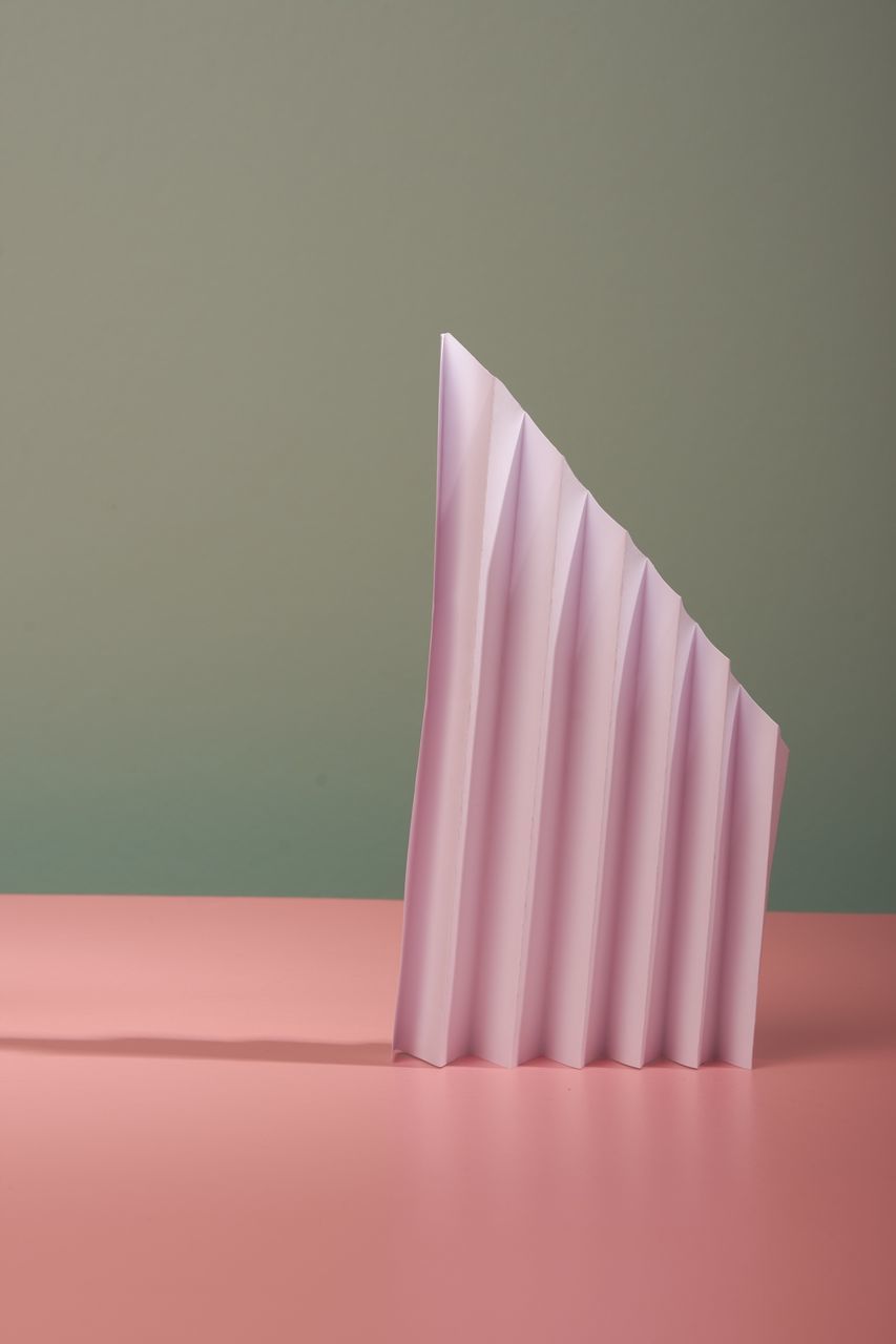 Close-up of pink paper on table against wall