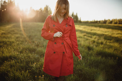 Woman standing on field against sky during sunset