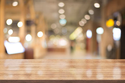 Defocused image of illuminated lights on table at restaurant