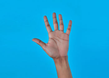 Close-up of hand over blue background
