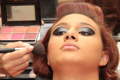 Close-up of beautician applying make-up on woman