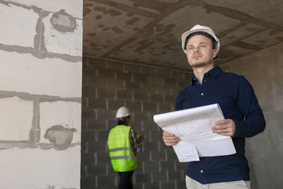 Portrait of young man standing against wall