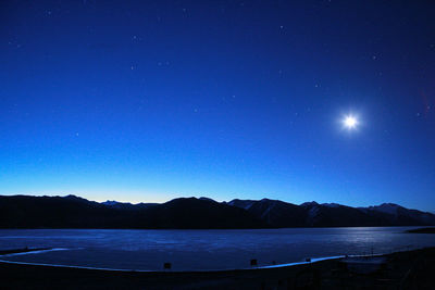 Scenic view of lake against clear blue sky at night