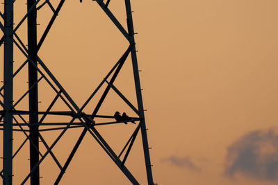 Low angle view of silhouette electricity pylon against sky