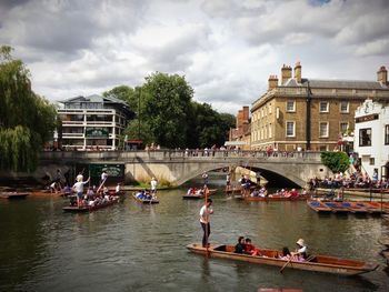 People in river against cloudy sky