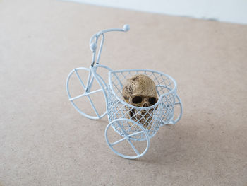Close-up of human skull in toy tricycle on table