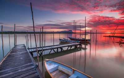 Sailboats moored in lake against sky during sunset