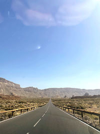 Road amidst field against sky