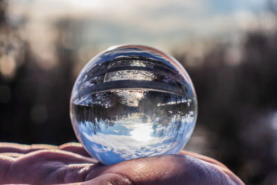 Reflection of person hand holding glass of crystal ball