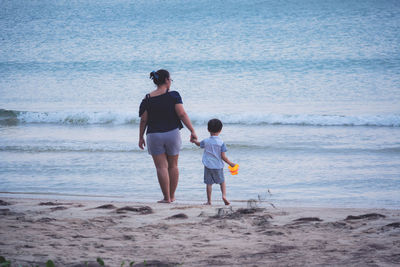 Full length of mother and daughter walking on beach