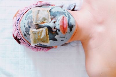 High angle view of woman with facial mask lying on bed