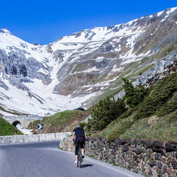 Rear view of man with bicycle on road