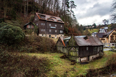 House amidst trees and plants on field against sky