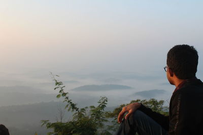 Rear view of man looking at mountains against sky