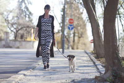 Woman with dog standing against tree