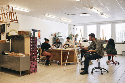 Male and female students practicing painting in art class