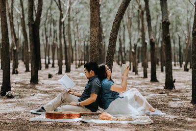 Young couple sitting on tree trunk in forest