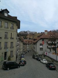 Cars on street by buildings against sky