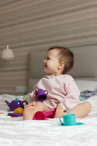 Portrait of cute baby boy sitting on bed at home