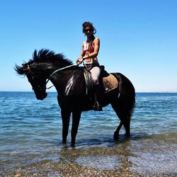 Woman riding horse in sea