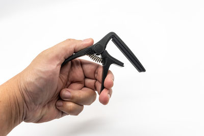 Close-up of hand holding cigarette over white background