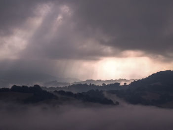 Scenic view of cloudscape against mountains during sunset