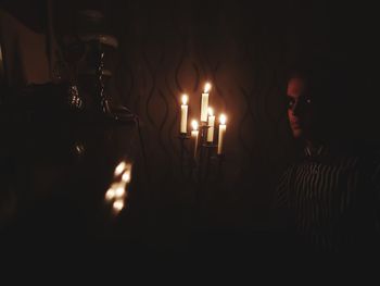 Man holding illuminated candles in dark room