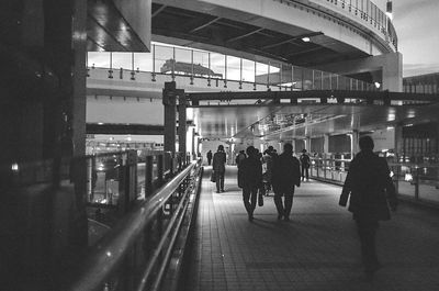 People walking on illuminated bridge in city