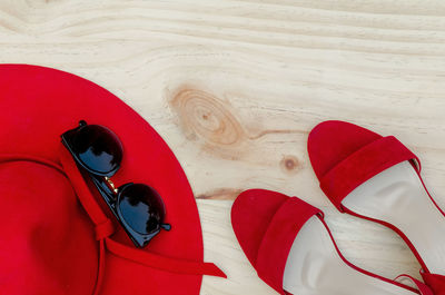 Directly above shot of sunglasses with sun hat by sandals on wooden table