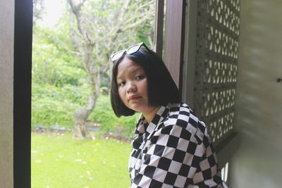 Portrait of young woman looking through window