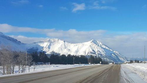 Road by mountains against sky during winter