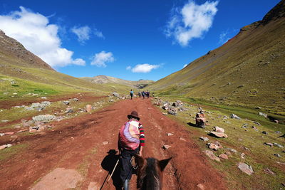 Rear view of woman riding motorcycle on landscape against sky