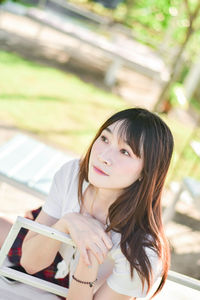 Portrait of young woman looking away while standing outdoors