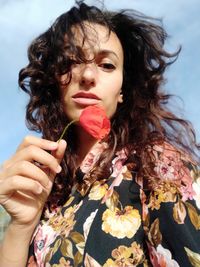 Portrait of young woman holding a poppy flower