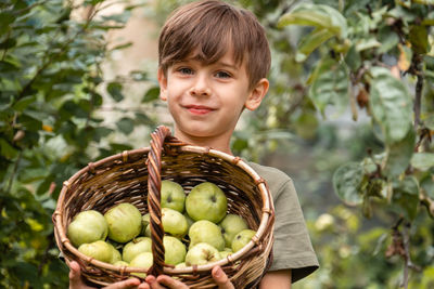 Portrait of young woman holding apples in basket