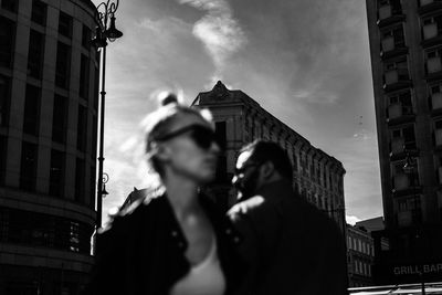 Low angle view of people standing against buildings in city