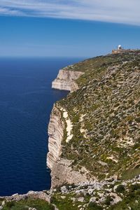 Scenic view of sea by cliff against sky