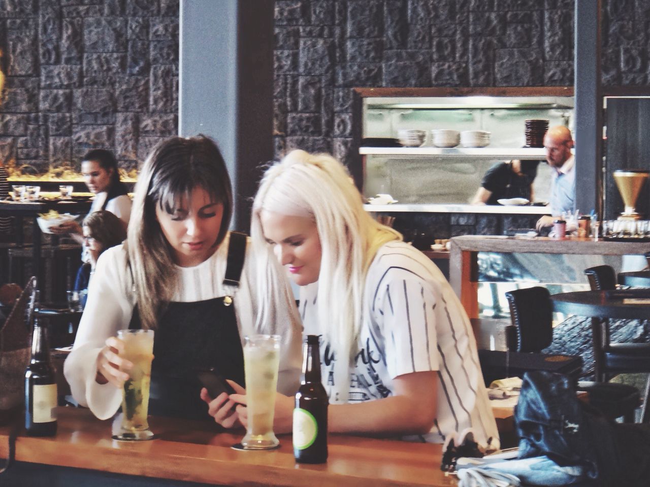 Two women texting at a bar