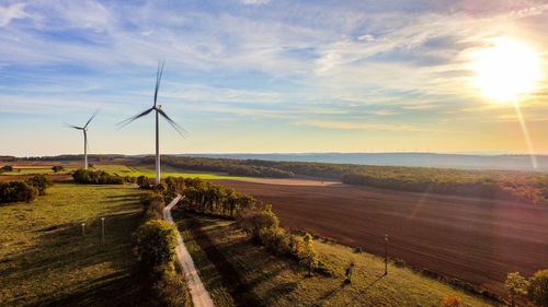 Windmill on field against sky during sunset