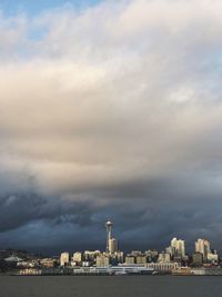 City at waterfront against cloudy sky