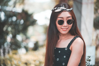 Smiling young woman wearing sunglasses looking away