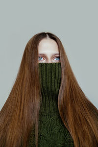 Modern portrait of a girl in a green sweater, hiding her face as in a protective mask