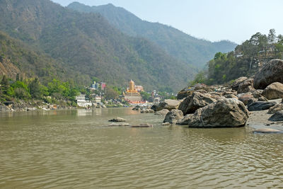 Scenic view of sea by rocks and mountains against sky